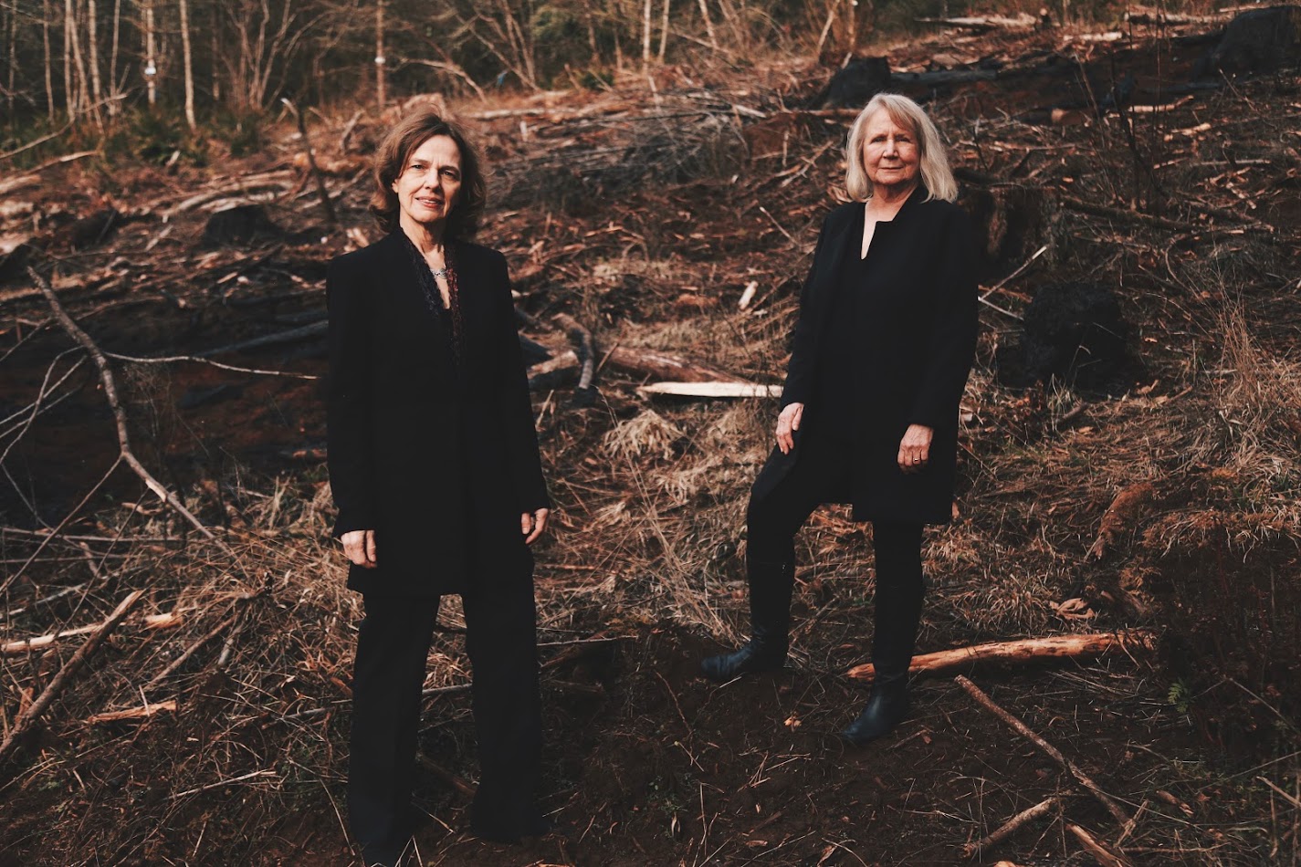 A photo of the author and her collaborator, concert pianist Rachelle McCabe, standing in a clearcut forest in Oregon.